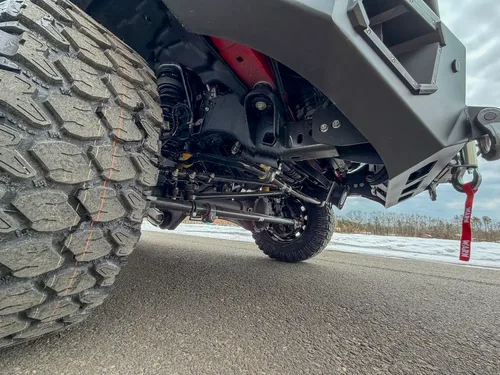 Front axle and tire tread close-up from low angle.